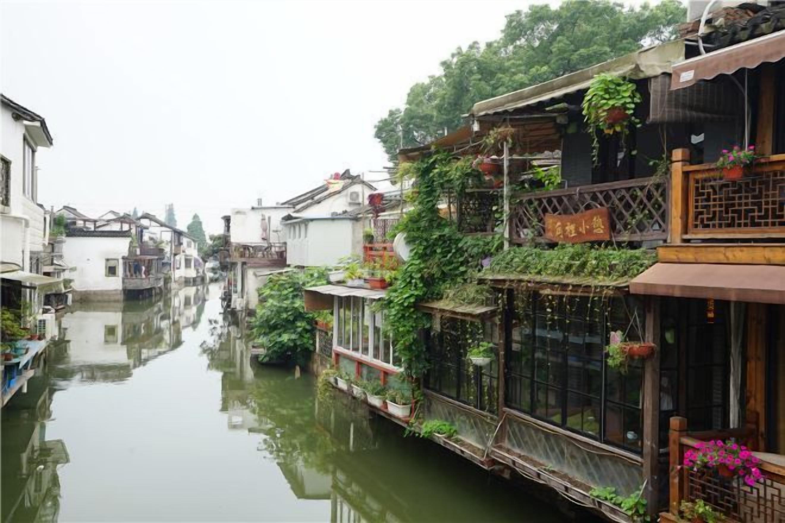 A narrow waterway flanked by traditional buildings with balconies adorned with plants and flowers.