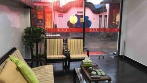 A room with a sofa, striped chairs, a small table with decorative items, and a view through a glass door. - Chang'an Hotel (Zhujiajiao Ancient Town Branch, Qingpu, Shanghai) (Shanghai)