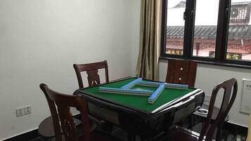 Una habitación con mesa de billar, cuatro sillas de madera y una ventana con vistas a la arquitectura tradicional.