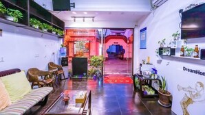 A hotel lobby with a sofa, chairs, a coffee table, potted plants, and a red carpet leading to a bar area. - Chang'an Hotel (Zhujiajiao Ancient Town Branch, Qingpu, Shanghai) (Shanghai)