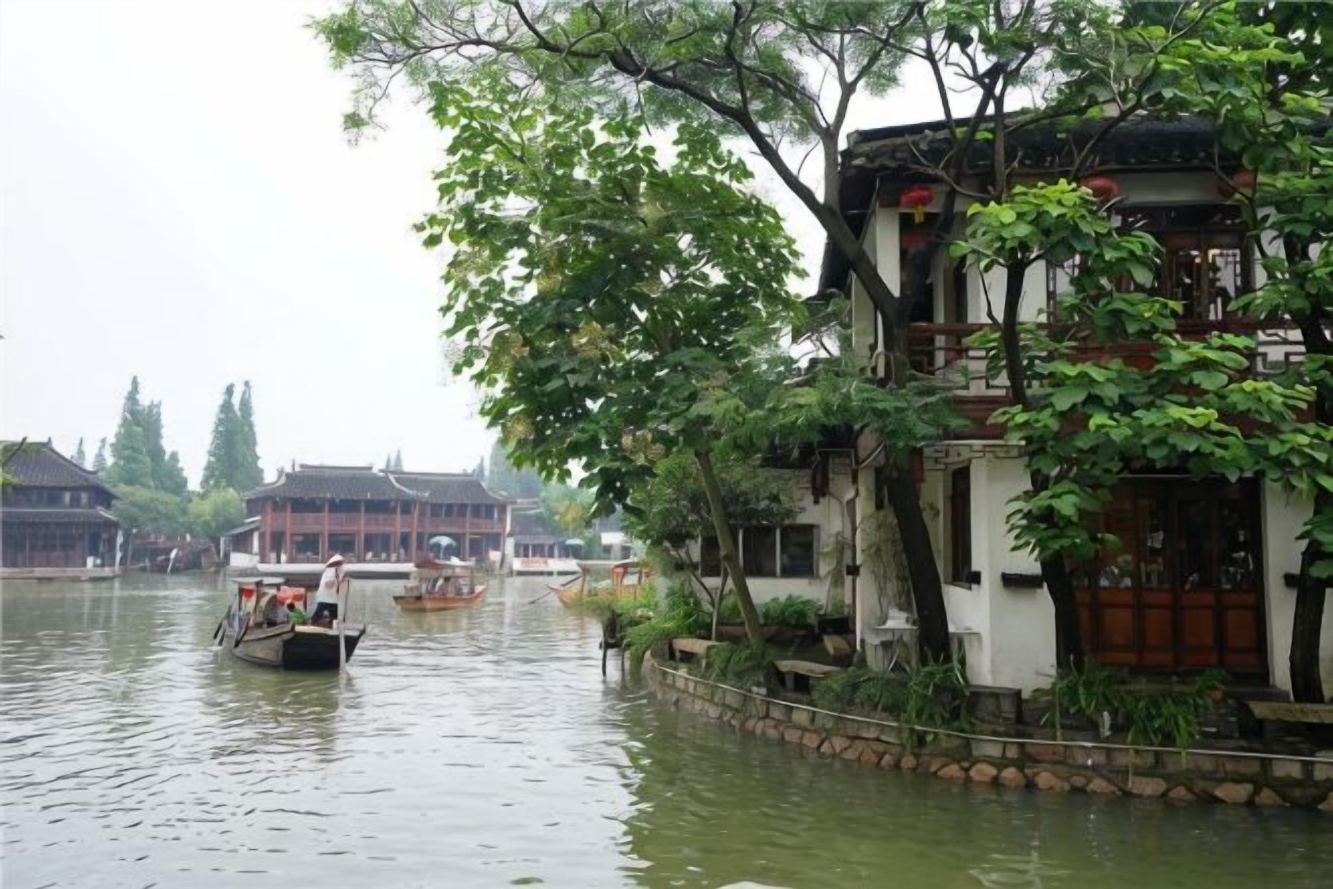 Un bâtiment traditionnel, avec un canal en façade, des bateaux et de la verdure.