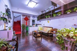 A living room with a sofa, a coffee table, and a dining table with chairs. There are potted plants and a staircase leading to an upper level. - Chang'an Hotel (Zhujiajiao Ancient Town Branch, Qingpu, Shanghai) (Shanghai)