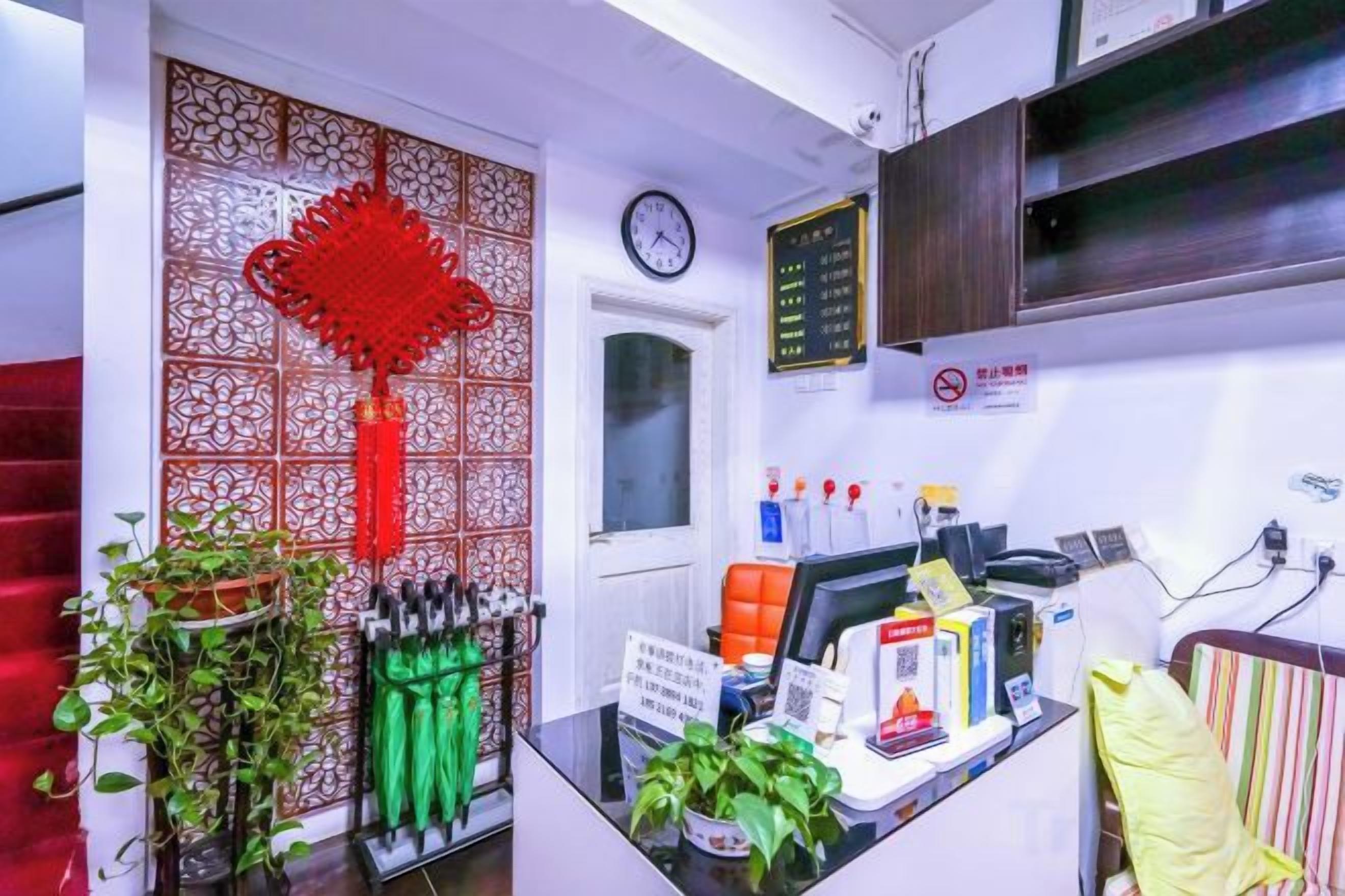 A reception area with a desk, a clock, a wall-mounted menu board, and a decorative red hanging ornament.