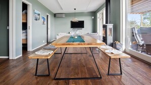 A modern living room with a wooden dining table, a fireplace, and a large window. - 5 Star Holiday Home in Lottorp (Löttorp)