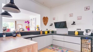 A modern kitchen with a central island, a built-in oven, and a refrigerator.