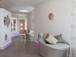 A modern interior with a curved seating area, wooden wall art, and a wooden door with circular windows.