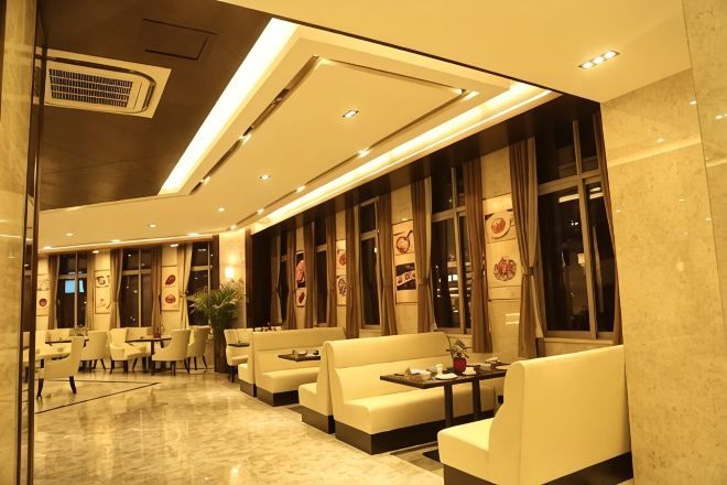 A modern hotel lobby with seating areas, a reception desk, and large windows.