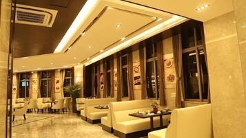 A modern hotel lobby with seating areas, a reception desk, and large windows.