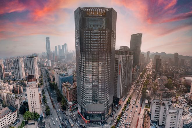 A high-rise building with a grid-like facade, surrounded by a dense urban environment with other tall buildings and busy streets.