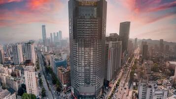 A high-rise building with a grid-like facade, surrounded by a dense urban environment with other tall buildings and busy streets.