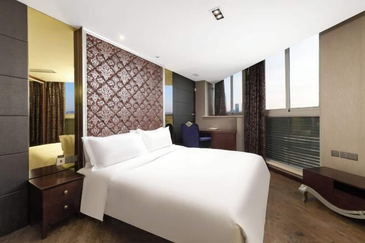 Een moderne hotelkamer met een groot bed, een bureau en uitzicht op de stad.