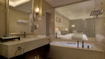 A modern bathroom with a large mirror, a bathtub, and a vanity with toiletries.
