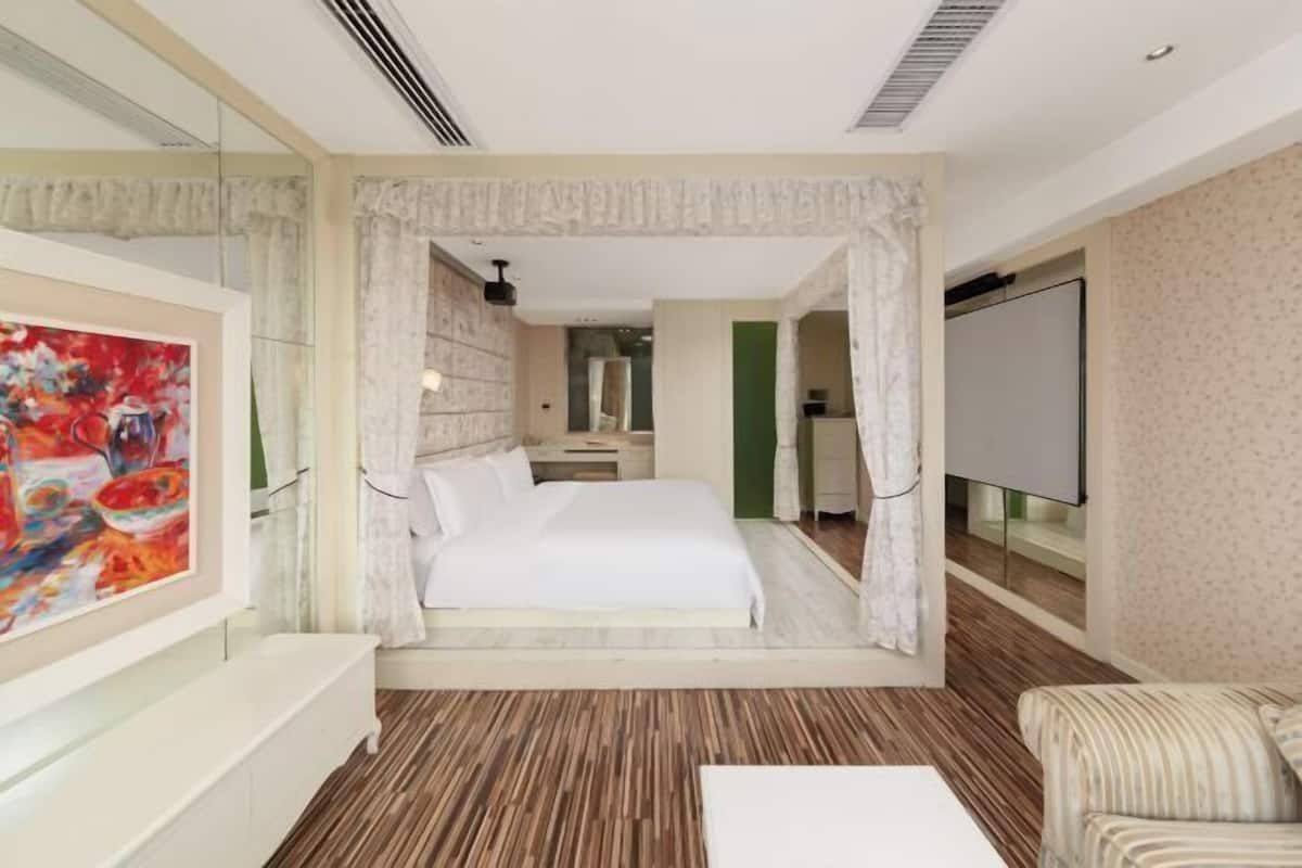 Een moderne hotelkamer met een groot bed, een televisie, een schilderij en een houten vloer.