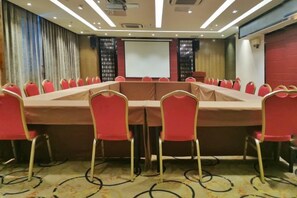 A conference room with a long table, red chairs, and a projector screen. - BaiLing Nicesoe Hotel (Guiyang Spray Pool Zilinan) (Guiyang)
