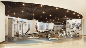 A modern gym with various exercise equipment, large windows, and a curved ceiling design. - BaiLing Nicesoe Hotel (Guiyang Spray Pool Zilinan) (Guiyang)