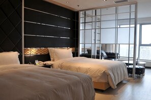 Een moderne hotelkamer met twee bedden, een groot raam en uitzicht op de stad.