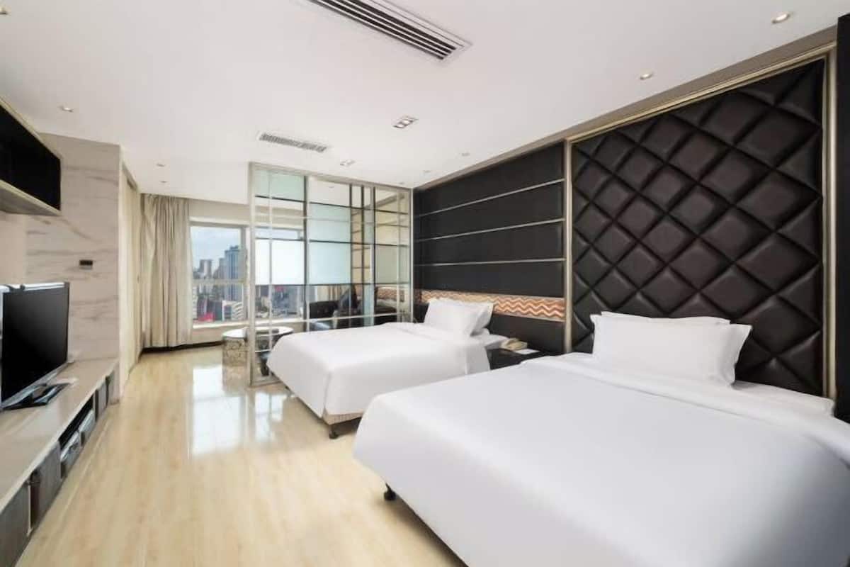 Een moderne hotelkamer met twee bedden, een flatscreen televisie en uitzicht op de stad.