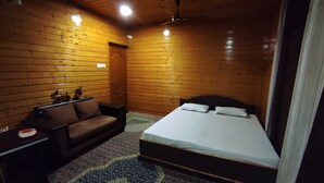A wooden-paneled room with a bed, a sofa, and a nightstand. - Lajawab Homestay  (Srinagar)