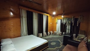 A hotel room with a bed, a sofa, a desk, and a ceiling fan. - Lajawab Homestay  (Srinagar)