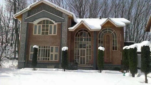 A two-story house with a brick facade, large windows, and snow on the roof and ground. - Lajawab Homestay  (Srinagar)