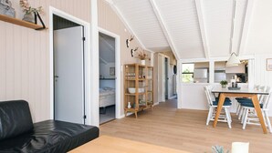 Ein modernes Interieur mit einem Holzespeisetisch, einer schwarzen Ledersofa, einem Bücherregal und einer Küchenzeile.