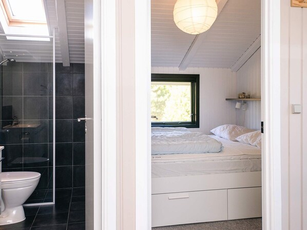 Une salle de bain moderne avec une douche à l’italienne en verre, des toilettes et une lucarne.