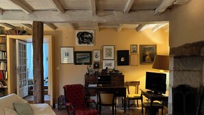 Un salón acogedor con chimenea, un sillón rojo, un sofá y una estantería llena de libros.
