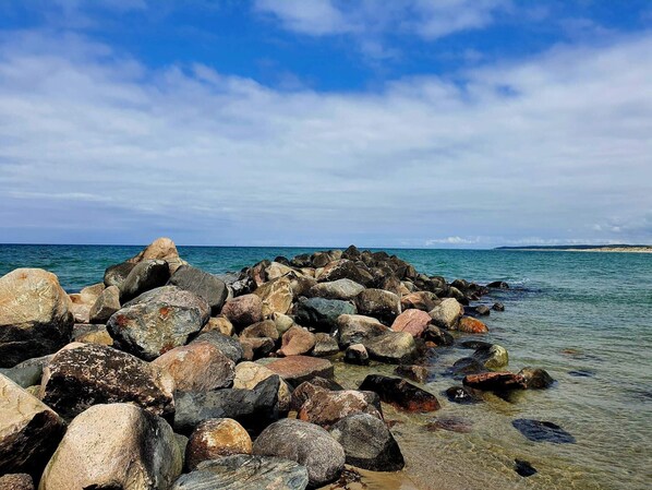 A rocky shoreline with clear water and a distant landmass.