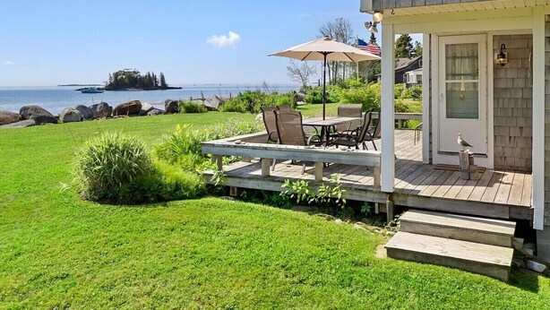 Une maison avec une terrasse, du mobilier d’extérieur et une vue sur l’océan.