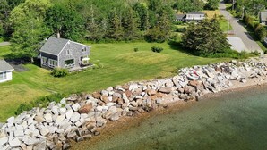 Une propriété située sur la côte, avec un mur en pierre, une maison et une zone herbeuse.