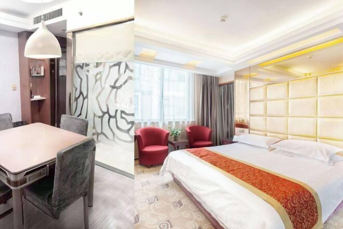 A hotel room with a bed, a dining table, and two chairs.