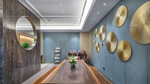 A modern conference room with a long wooden table, a large mirror, and decorative wall panels.