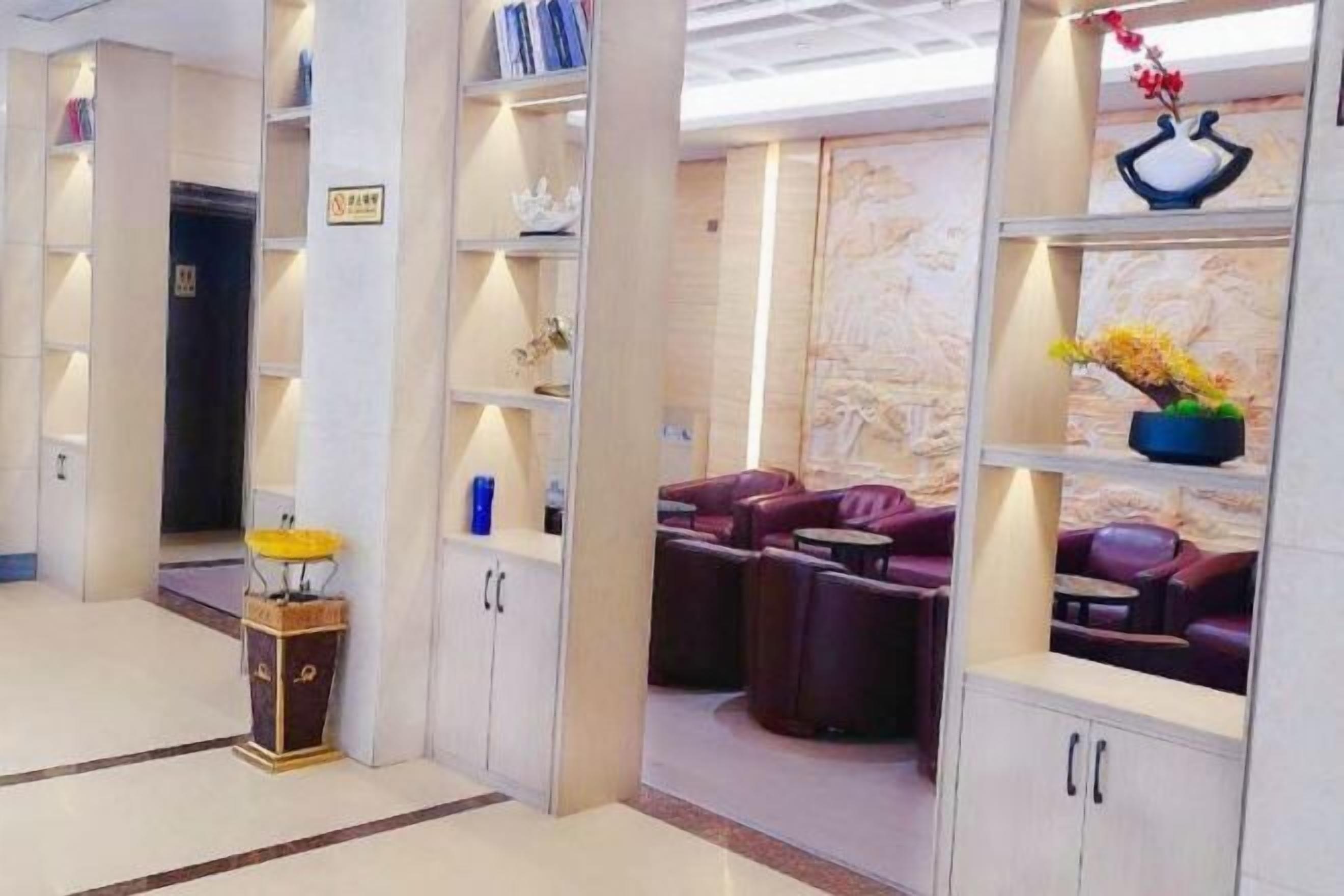 A modern lobby with seating areas, a reception desk, and decorative shelves.