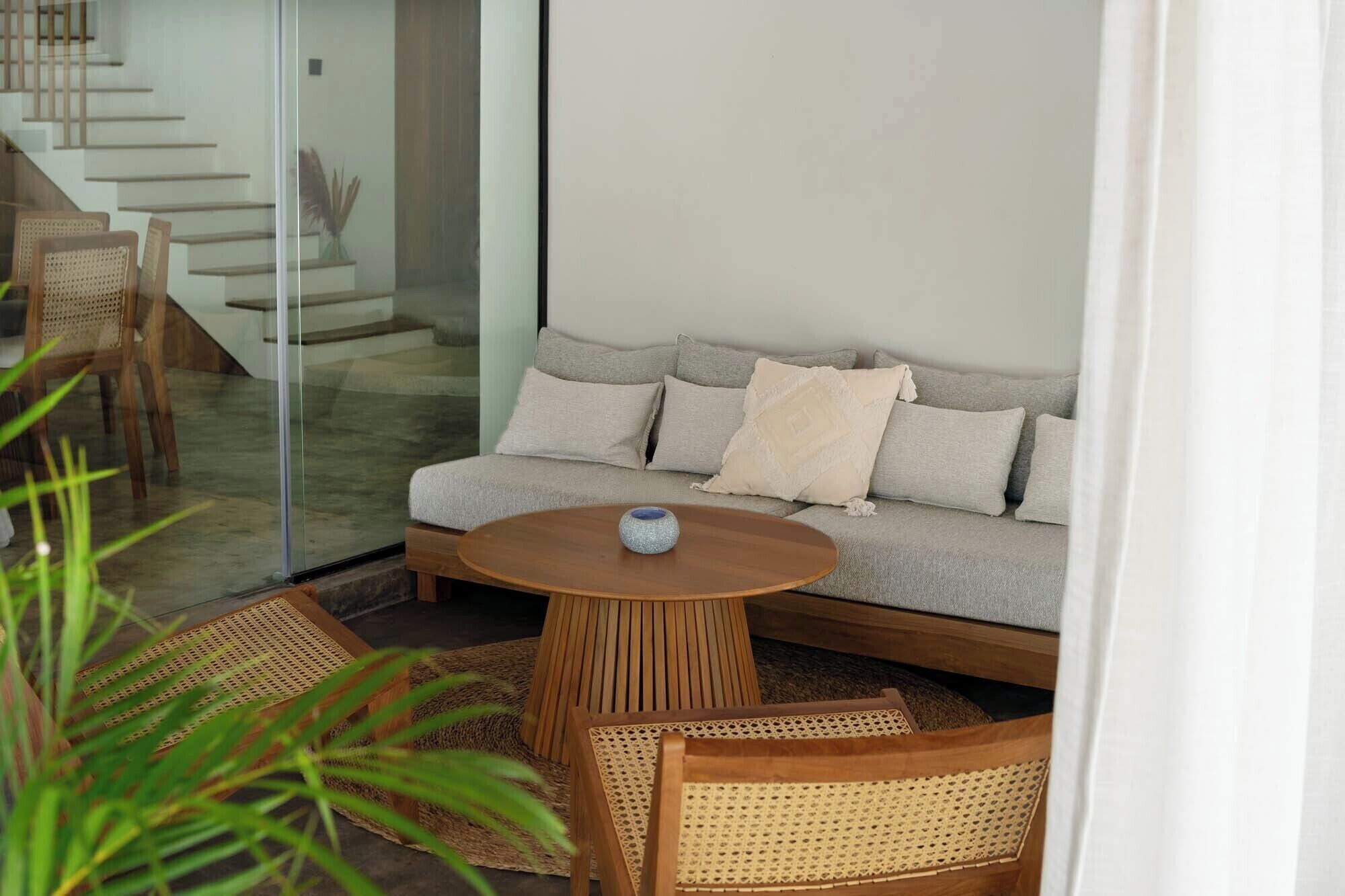 A modern living area with a sofa, a round wooden table, and wicker chairs.