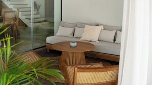Un salón moderno con sofá, mesa redonda de madera y sillas de mimbre.