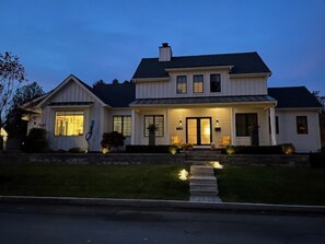 Une maison à deux étages avec un porche à l’avant, une allée et une pelouse bien entretenue.