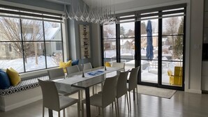 Un comedor moderno con una mesa de vidrio y sillas, ventanas amplias y vistas al exterior.