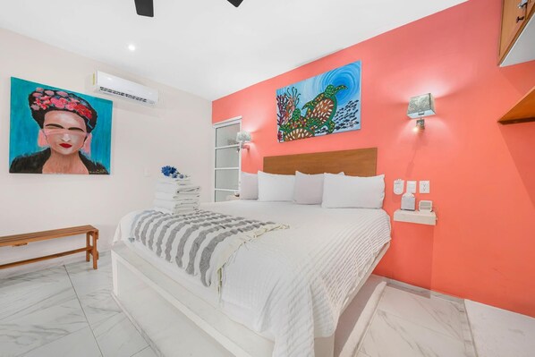 Una camera da letto con un letto, un comodino, una lampada a parete e opere d'arte.