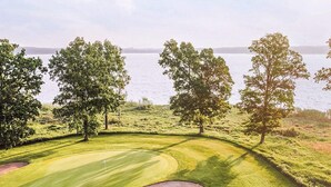 A golf course with a water body in the background, surrounded by trees. - Serene Lakehouse With Rowing Boat (Vittsjo)