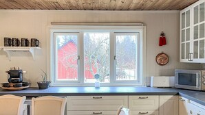 A kitchen with a large window, white cabinets, a microwave, and a coffee maker. - Serene Lakehouse With Rowing Boat (Vittsjo)