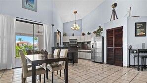 A modern kitchen with a dining area, a refrigerator, and a view of the outside.