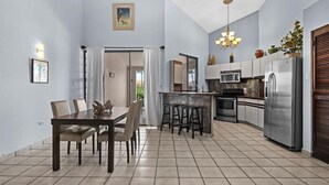 A modern kitchen with a central island, stainless steel appliances, and a dining area with a table and chairs.