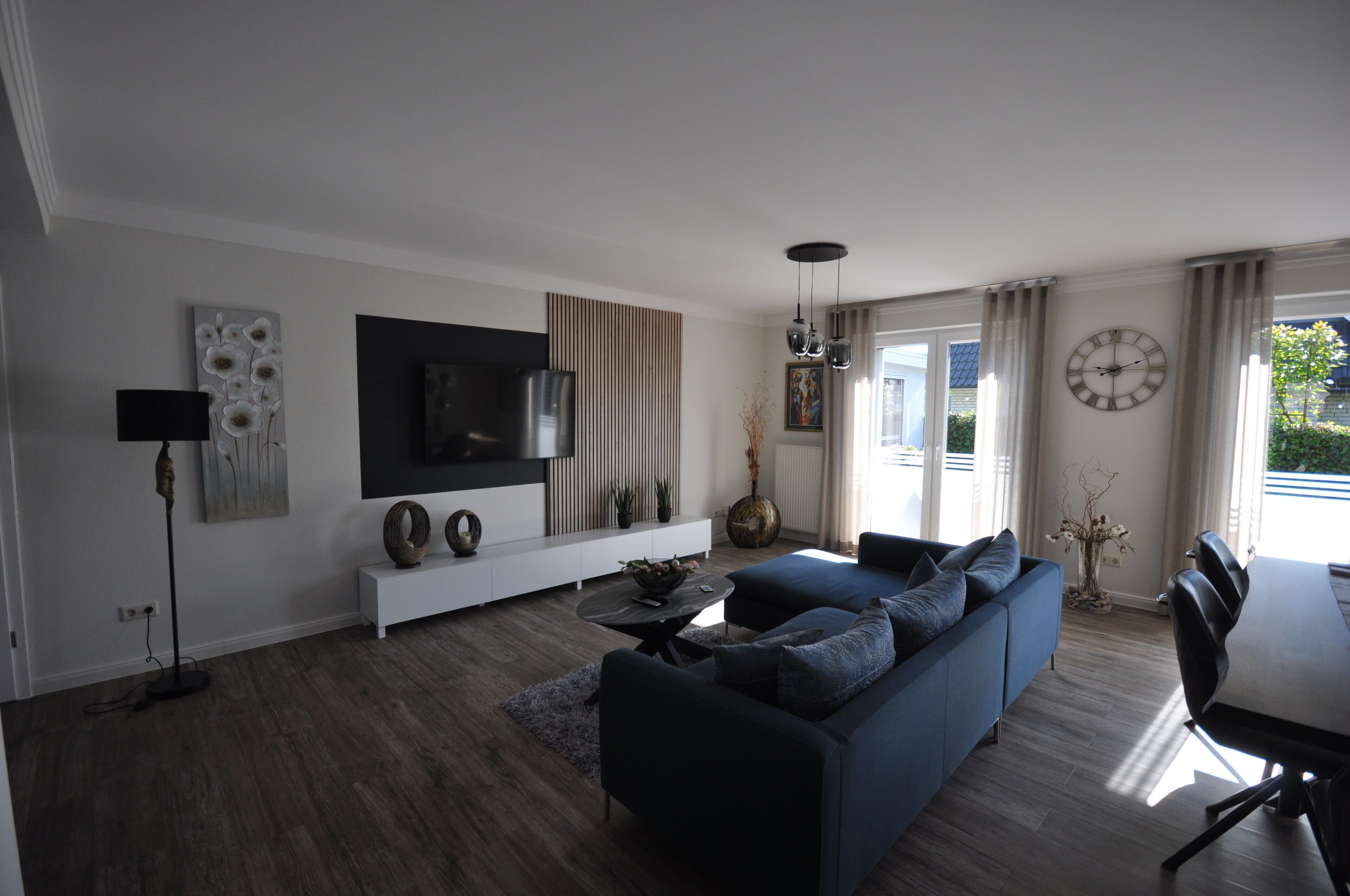A modern living room with a large TV, sofa, and dining area.