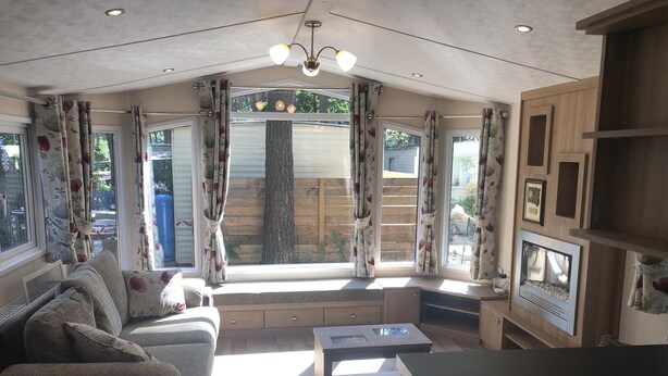 A cozy living room with a sofa, coffee table, and built-in TV. Large windows with curtains offer views of the outside. - Chalet Near Antwerp With Nature Trails (Lille)