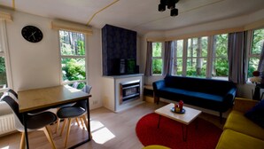 A modern living room with a dining area, a sofa, a red rug, and a fireplace.