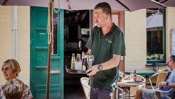 An outdoor seating area with a waiter serving drinks.