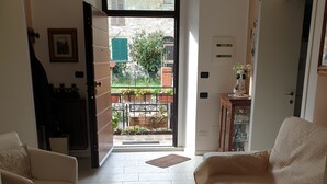 Een ruime woonkamer met een grote bank, een bijzettafeltje en uitzicht op het balkon.