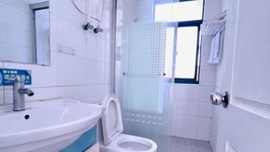 A bathroom with a white sink, a toilet, and a glass shower enclosure. - Ziqi Hotel (Shanghai Bay University Town) (Shanghai)