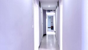 A long, narrow hallway with white walls and a shiny tiled floor, leading to a door at the end. - Ziqi Hotel (Shanghai Bay University Town) (Shanghai)