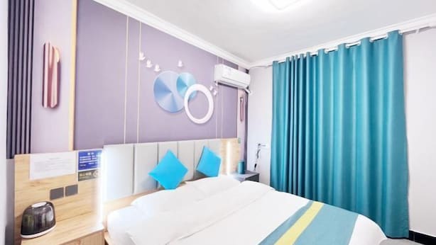 A modern hotel room with a bed, a bedside table with a kettle, a wall-mounted air conditioner, and a curtain. - Ziqi Hotel (Shanghai Bay University Town) (Shanghai)